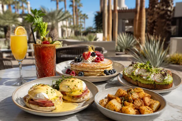 Eggs Benedict, pancakes, avocado toast, breakfast potatoes, and brunch cocktails on a sunny Las Vegas patio