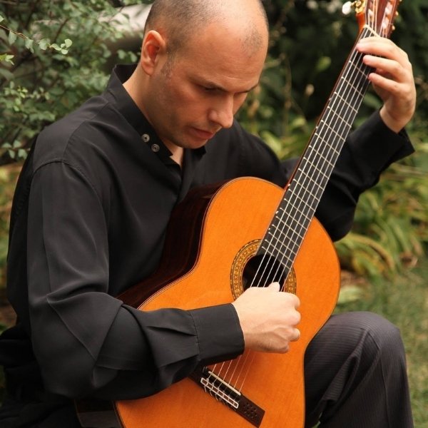 Argentine composer and classical guitarist Carlos Pavan performing live with an acoustic guitar.