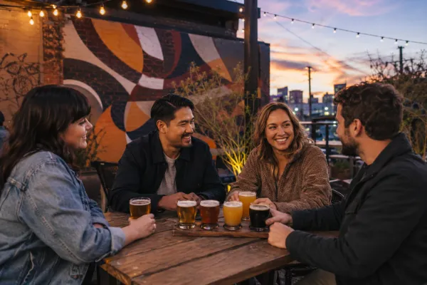 Friends enjoying craft beer on a Las Vegas Arts District brewery patio at sunset
