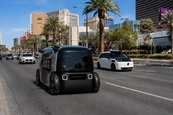 Zoox and Waymo driverless robotaxis travel along the Las Vegas Strip in daytime traffic.