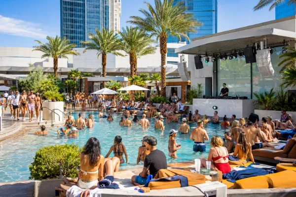 Guests enjoy a Las Vegas resort pool party with a DJ, cabanas, palm trees, and a lively Labor Day weekend atmosphere.