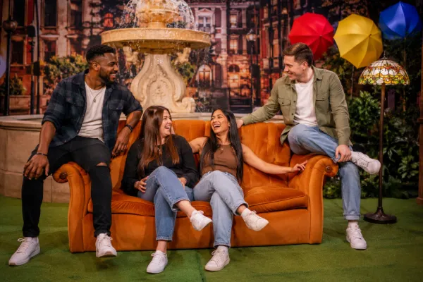 Friends pose on an orange couch beside a fountain at The FRIENDS Experience Las Vegas.