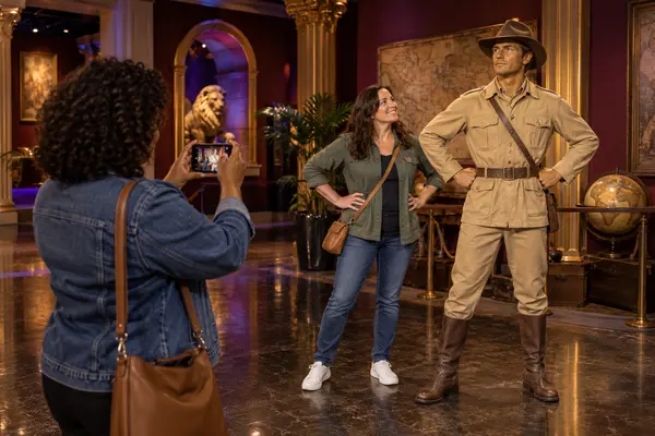 Visitors take a playful photo with a lifelike wax adventurer figure inside a Las Vegas museum gallery.