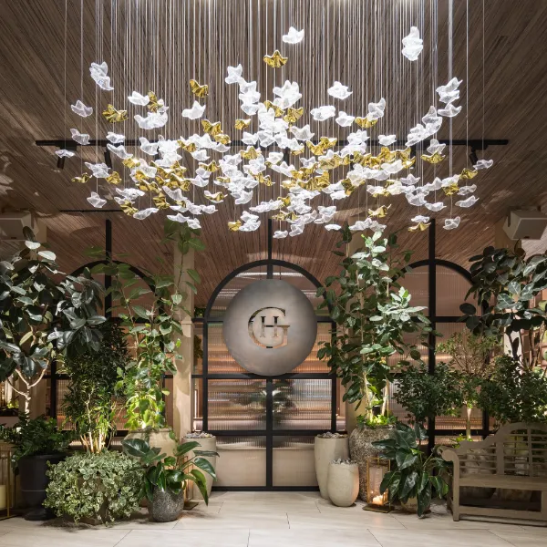 Guest House Las Vegas entrance with lush potted plants, a GH logo, and suspended white and gold butterfly decorations.