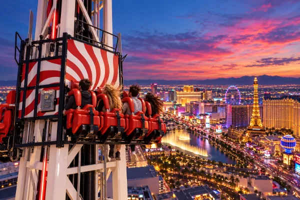 Artist's illustration of Eye Dropper riders facing the Las Vegas Strip beneath a pink and blue sunset sky.