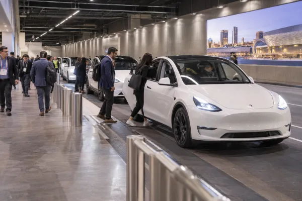 Convention attendees board white Tesla vehicles at a Las Vegas Convention Center Loop station