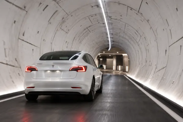White Tesla travels through an illuminated Las Vegas Loop tunnel toward an underground station