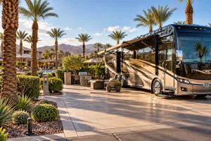 Luxury Class A motorcoach at an upscale Las Vegas RV resort with palm trees, resort amenities, and desert mountain views