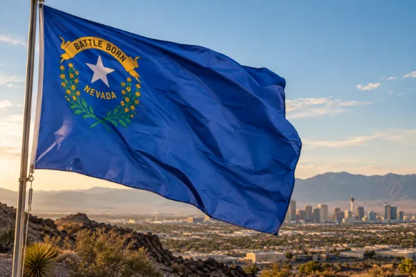 Nevada state flag flying above the Las Vegas Valley with desert mountains in the background for Nevada Day.