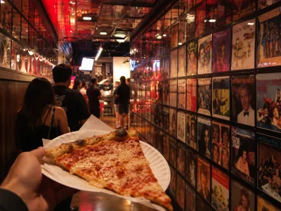 Secret Pizza at The Cosmopolitan in Las Vegas with a fresh pizza slice and the hidden pizzeria setting